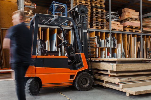Forklift carrying heavy wood planks and others items.