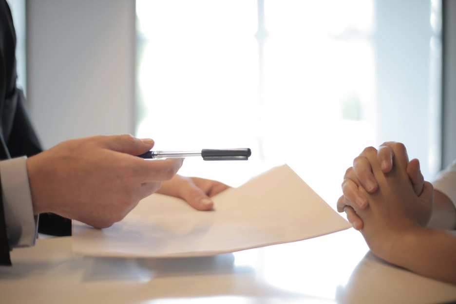 A man handing over the pen and docs to his client.